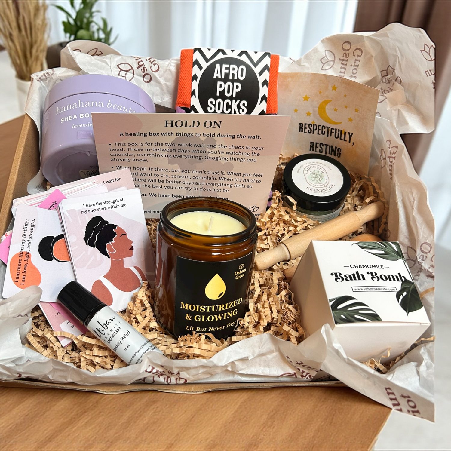 The Hold On Box: a candle, affirmation deck, socks, bath bomb, and anxiety oil packed in tissue