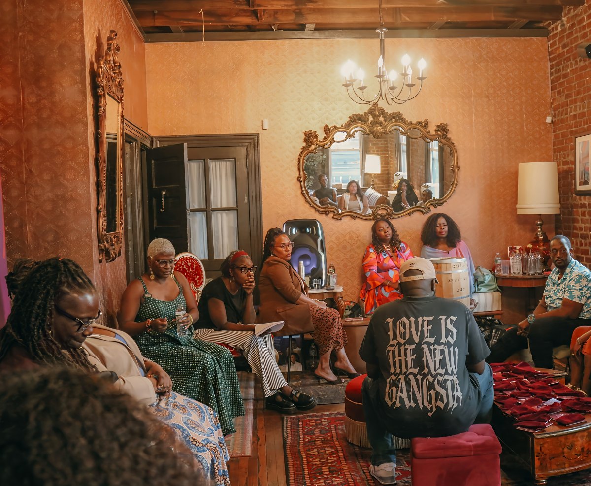 A room of people seated in a circle in conversation at an Oshun Griot community night in Jersey City
